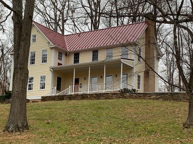 red standing seam metal roof panels installed on farmhouse porch and main roof