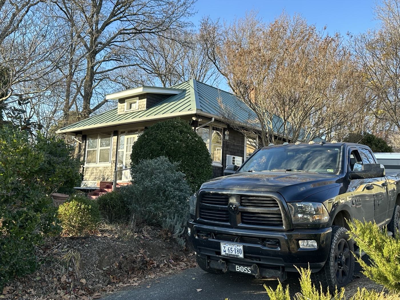 gray standing seam metal roof on barn building with service truck