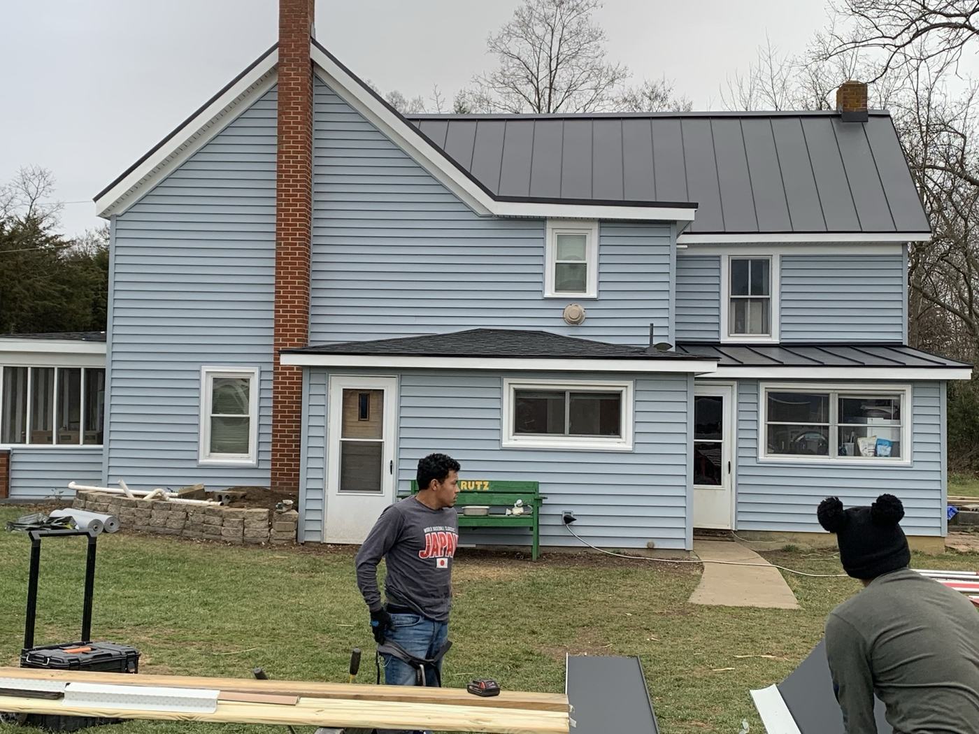 white farmhouse with black standing seam metal roof and front porch